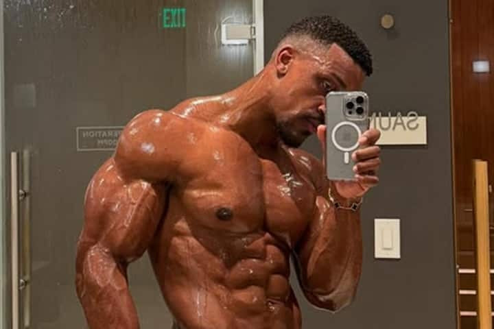 Ashton Hall showing his muscular body physique in a mirror selfie, highlighting his fitness and toned muscles.